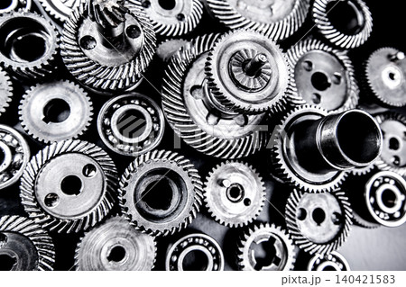 Metal gears and mechanical parts arranged on a flat surface in an industrial setting Metal gears and mechanical parts arranged on a flat surface in an industrial setting 140421583