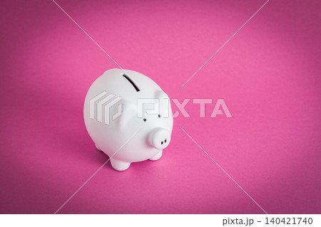 White piggy bank stands on pink background while saving money for future plans and goals White piggy bank stands on pink background while saving money for future plans and goals 140421740