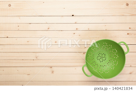 Green colander on wooden table surface with clean lines and simple design Green colander on wooden table surface with clean lines and simple design 140421834
