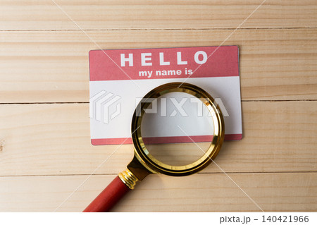 Magnifying glass over a name tag on a wooden table Magnifying glass over a name tag on a wooden table 140421966