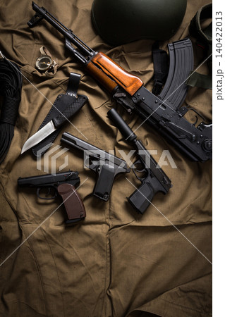 Various firearms and gear on a fabric surface in a military setting during daytime Various firearms and gear on a fabric surface in a military setting during daytime 140422013