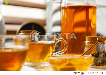 Cup of hot black tea on white table with dry tea jar Cup of hot black tea on white table with dry tea jar 140422181