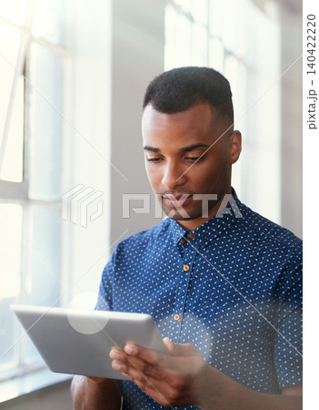 Businessman, tablet and reading at window for communication, internet search or networking in office. Entrepreneur, african employee or serious with technology for startup email or planning at work Businessman, tablet and reading at window for communication, internet search or networking in office. Entrepreneur, african employee or serious with technology for startup email or planning at work 140422220
