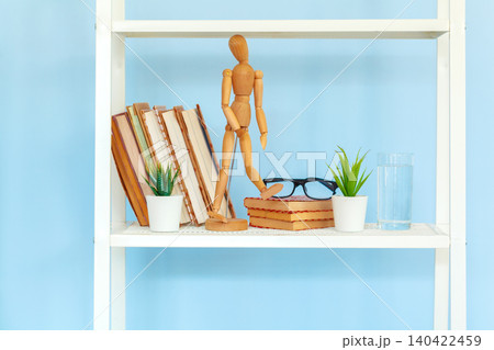 White metal rack with books against blue background White metal rack with books against blue background 140422459
