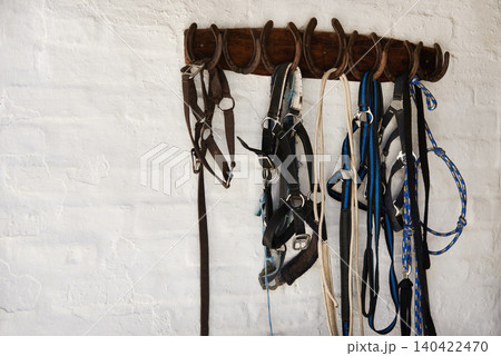 Riding bridle, tack and horseshoe in wall leather, rope and metal or steel on farm. Countryside, equestrian and wooden with rein for rural, western and horse gear for training or competition Riding bridle, tack and horseshoe in wall leather, rope and metal or steel on farm. Countryside, equestrian and wooden with rein for rural, western and horse gear for training or competition 140422470