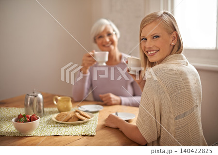 Portrait, happy woman and senior mother drinking coffee at breakfast, bonding and smile in house. Face, elderly mom and adult with tea cup at table, food and family eating cookies at home together 140422825