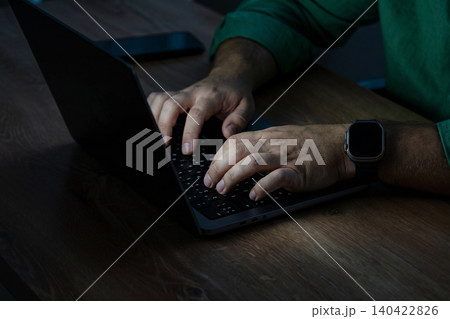 Man typing on laptop at night in a dimly lit room with focus on hands Man typing on laptop at night in a dimly lit room with focus on hands 140422826