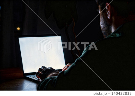 Man types on a laptop in dim light during nighttime at home Man types on a laptop in dim light during nighttime at home 140422835