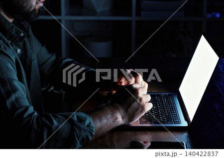 Person works on laptop in dark room during late night hours Person works on laptop in dark room during late night hours 140422837