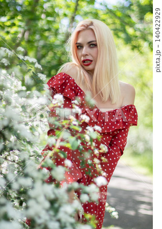 Blonde Woman Leaning Near White Flowers Outdoors Blonde Woman Leaning Near White Flowers Outdoors 140422929