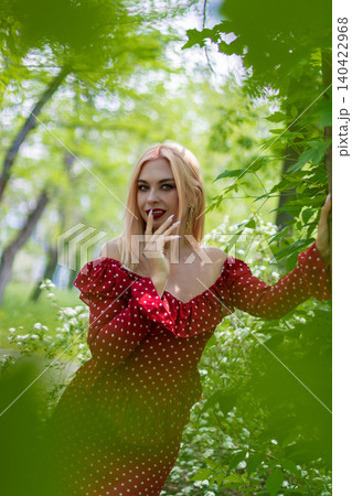 Blonde Woman Framed by Green Leaves in Forest Blonde Woman Framed by Green Leaves in Forest 140422968