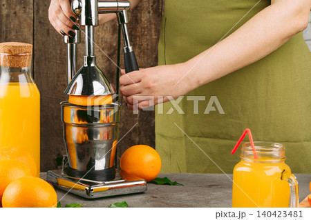 Woman using orange juicer apparatus at home Woman using orange juicer apparatus at home 140423481