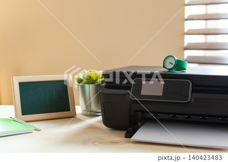 Front view of a black printer machine on a table 140423483