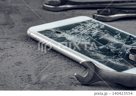 Crashed smartphone with repairing tools on grey background 140423554