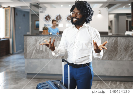 Black businessman with packed luggage standing in hotel lobby 140424129