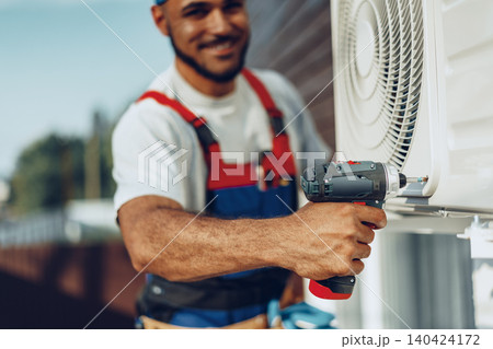 Repairman in uniform installing the outside unit of air conditioner 140424172