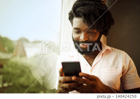 Bearded young african american man looking at his smartphone Bearded young african american man looking at his smartphone 140424250