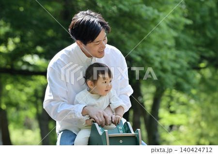 公園でスプリング遊具を楽しむ娘と父親 140424712