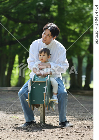公園でスプリング遊具を楽しむ娘と父親 140424714