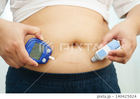 Asian woman injecting herself diabetes injecting insulin in stomach at home. Asian woman injecting herself diabetes injecting insulin in stomach at home. 140425024