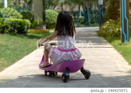 Cute Asian Little Girl Riding Wiggle Car Outdoors in Sunny Park Cute Asian Little Girl Riding Wiggle Car Outdoors in Sunny Park 140425071