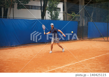 Exercise, sports or tennis and man with racket hitting ball on court for competition, game or match. Fitness, health and training with confident young athlete person outdoor in summer for action 140425115