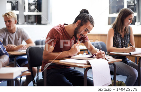 Man, class and writing notes in college, learning and knowledge on campus for education. Students, people and reading for information in book, planning and research for studying or revision for exams Man, class and writing notes in college, learning and knowledge on campus for education. Students, people and reading for information in book, planning and research for studying or revision for exams 140425379