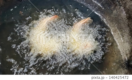Deep-frying breaded shrimp in hot boiling oil in a wok pan Deep-frying breaded shrimp in hot boiling oil in a wok pan 140425472