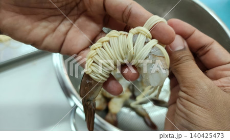 Chef hand wrapping raw shrimp with noodles for cooking appetizer Chef hand wrapping raw shrimp with noodles for cooking appetizer 140425473