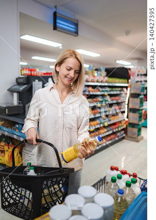 Woman buying cooking oil in grocery store Woman buying cooking oil in grocery store 140427395