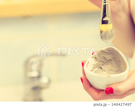 Female hand holding clay mud mask and brush. Skin care. Female hand holding clay mud mask and brush. Skin care. 140427497