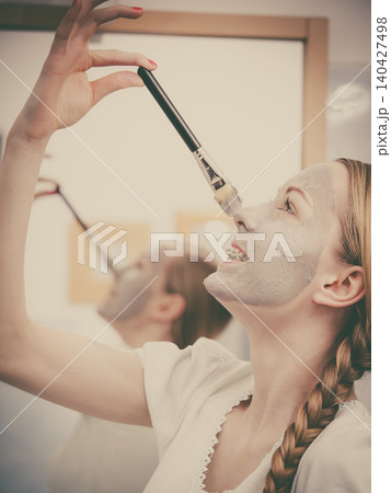 Woman applying with brush clay mud mask to her face 140427498