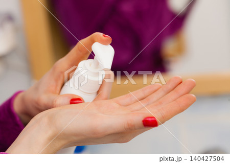 Woman applying hand cream on hands Woman applying hand cream on hands 140427504