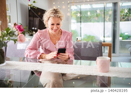 Woman smiling using phone at home Woman smiling using phone at home 140428195