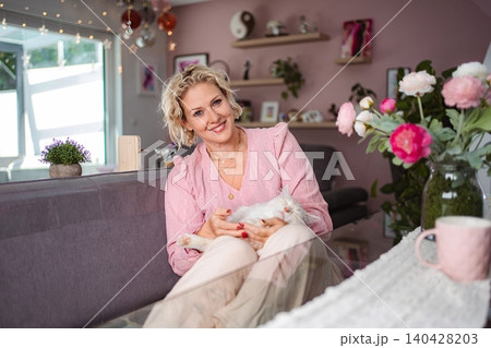 Woman smiling, holding white cat on sofa at home Woman smiling, holding white cat on sofa at home 140428203