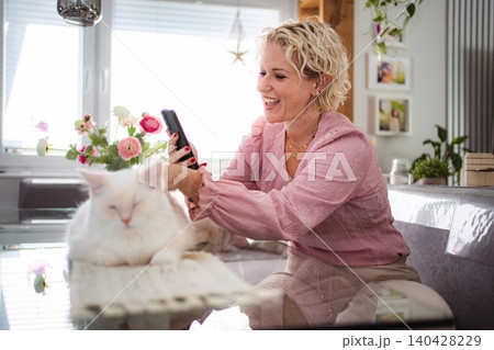 Woman laughing during video call with smartphone and cat 140428229