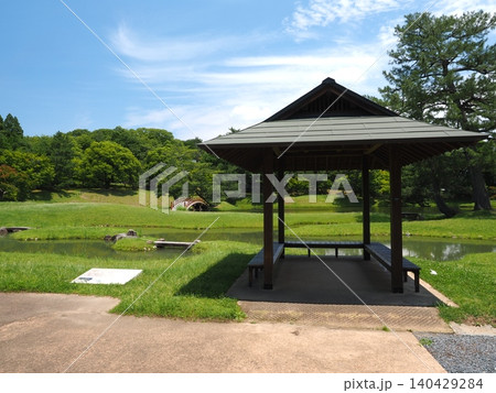 東屋の影に涼み、名勝を眺める贅沢。初夏の青空が広がる『旧大乗院庭園』の清々しい休憩風景 東屋の影に涼み、名勝を眺める贅沢。初夏の青空が広がる『旧大乗院庭園』の清々しい休憩風景 140429284