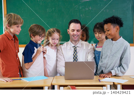 Caucasian male teacher and diverse pupils using laptop in classroom Caucasian male teacher and diverse pupils using laptop in classroom 140429421