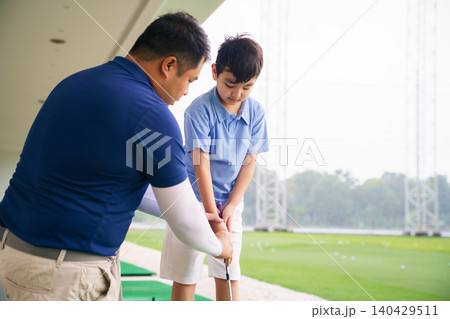 Professional golf coach teaching basic grip to young boy Professional golf coach teaching basic grip to young boy 140429511