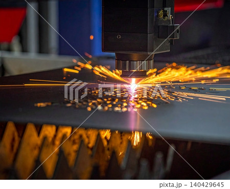 A powerful laser cutter meticulously carves intricate patterns into a metal surface 140429645