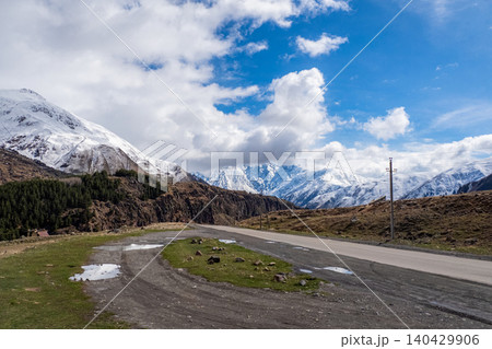 Snow-capped peaks rise behind a winding road 140429906