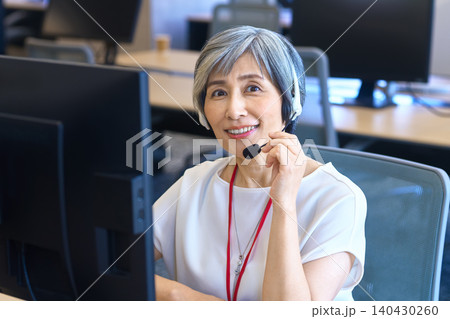 ヘッドセットを押さえて微笑むグレーヘア女性 ヘッドセットを押さえて微笑むグレーヘア女性 140430260