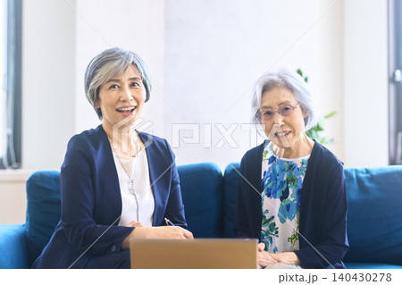 窓辺で荷物を前に談笑する二人のシニア女性 窓辺で荷物を前に談笑する二人のシニア女性 140430278