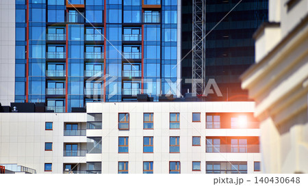 A low-rise residential building stands against a backdrop of tall glass buildings. An urban quarter of modern architecture. 140430648