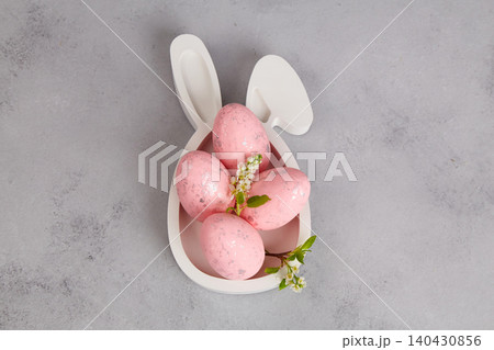 Pink Easter eggs with flowers on a white plate shaped like bunny ears Pink Easter eggs with flowers on a white plate shaped like bunny ears 140430856