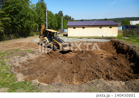 Backhoe loader leveling and moving soil near a trench at a residential construction site 140430881