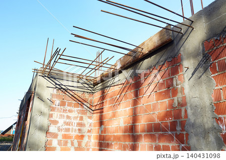 Construction site shows brick wall with exposed rebar and clear sky during the day Construction site shows brick wall with exposed rebar and clear sky during the day 140431098