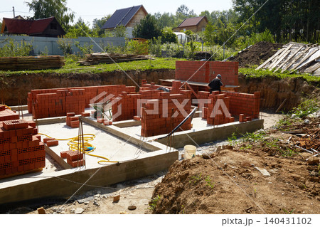 Workers are building solid brick walls of a house in a quiet suburban neighborhood. 140431102