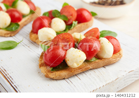 Bruschetta with mozzarella, cherry tomatoes, and basil on a serving board Bruschetta with mozzarella, cherry tomatoes, and basil on a serving board 140431212