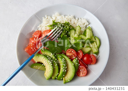 Hawaiian salmon poke bowl with cucumber, tomato,rice, chuka salad, sesame seeds, avocado. Hawaiian salmon poke bowl with cucumber, tomato,rice, chuka salad, sesame seeds, avocado. 140431231